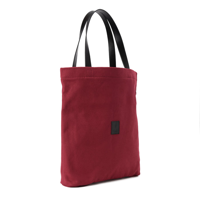 Red canvas shoulder bag with black handles, minimalist design, isolated on white background
