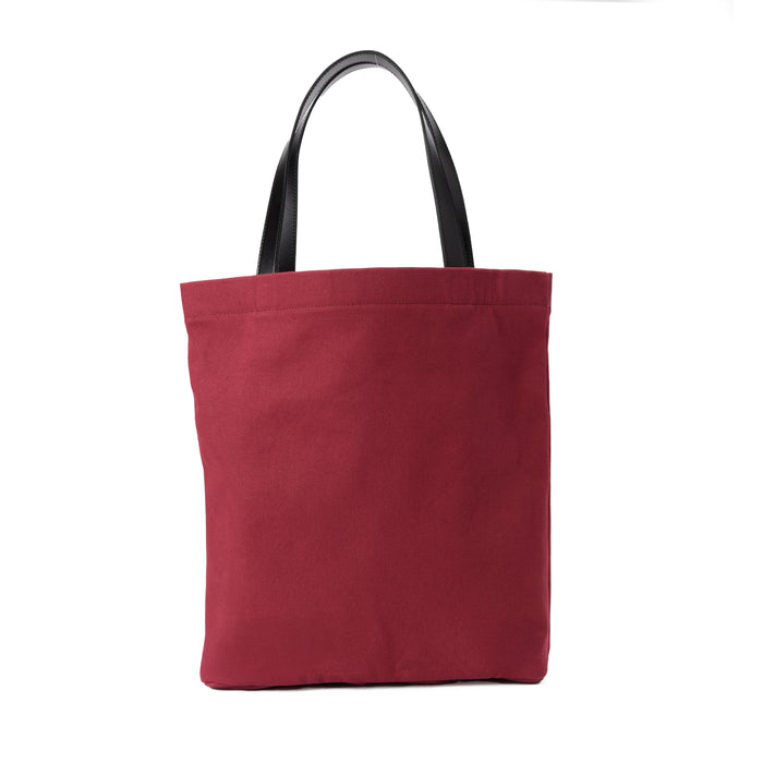 Red canvas tote bag with black handles on white background