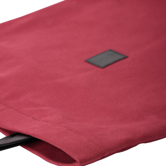 Close-up of a red canvas tote bag with black square patch detail