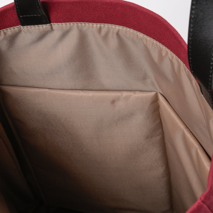 Interior close-up of a beige-lined tote bag with red fabric and black handle