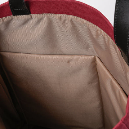Interior close-up of a beige-lined tote bag with red fabric and black handle