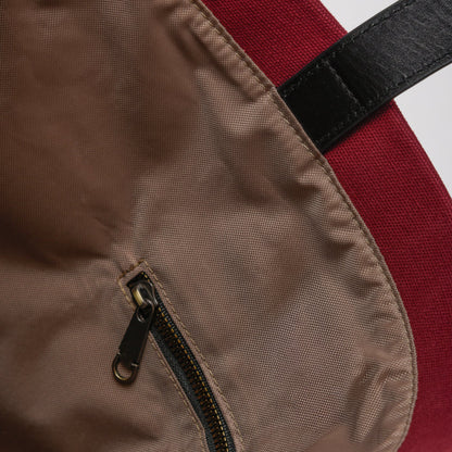 Close-up of brown zipper pocket on red fabric backpack with black strap