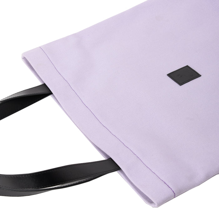 Lilac canvas shoulder bag with black leather handles and a small square patch