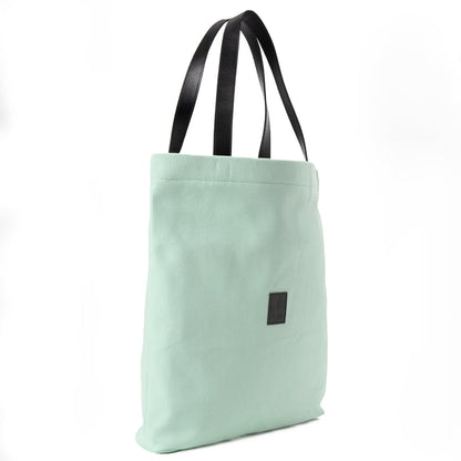 Mint green canvas shoulder bag with black handles on white background