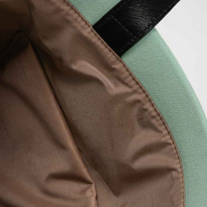 Close-up of green fabric bag with beige lining and black strap detail
