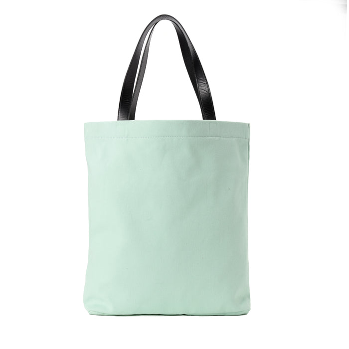Mint green canvas tote bag with black leather handles on white background