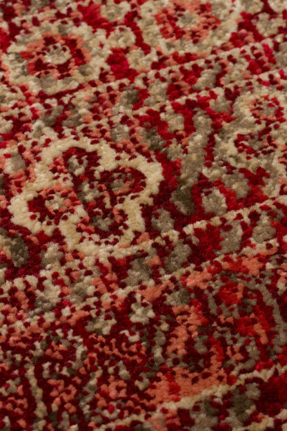Close-up of a red, coral, and beige rug featuring a traditional ornate floral medallion pattern with a textured pile.