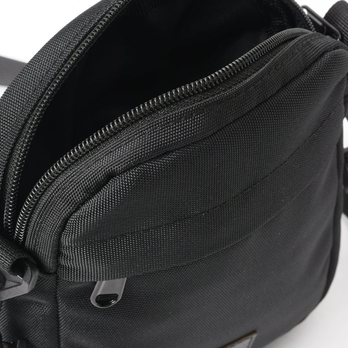 Close-up of black cross bag with zipper, textured fabric, and exterior pocket