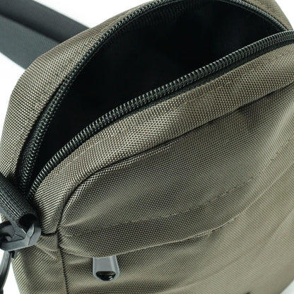 Close-up of a gray textured crossbody bag with black zipper and adjustable strap