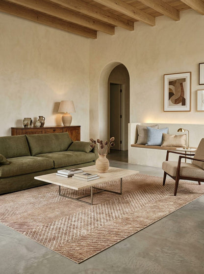 Tan and brown rug with a chevron pattern, styled in a modern living room with an olive green sofa.